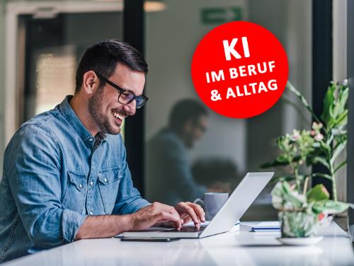 Ein Mann mit schwarzen Haaren sitzt an einem Office-schreibtisch, lächelnd vor seinem Laptop, ein roter Runder Button mit 'KI Im Beruf und Alltag' ist rechts neben ihm platziert.
