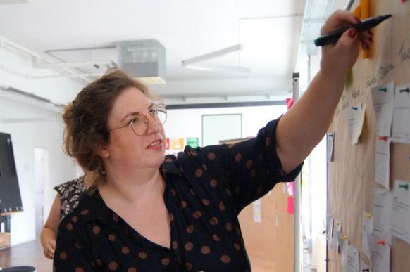Junge Frau, die an einem Board steht und mit einem Stift etwas notiert